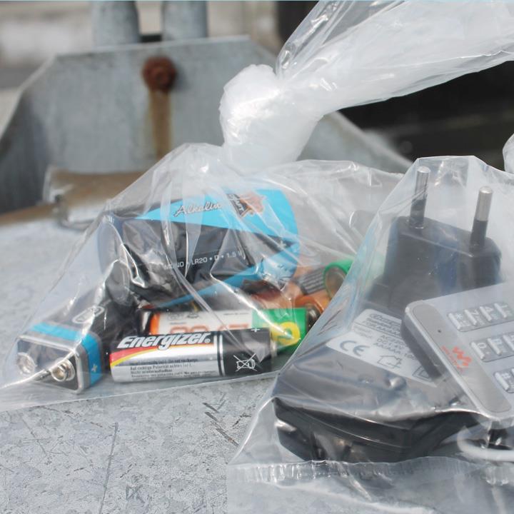 Poser med batterier og småt elektronikaffald ligger på låg af affaldsstativ